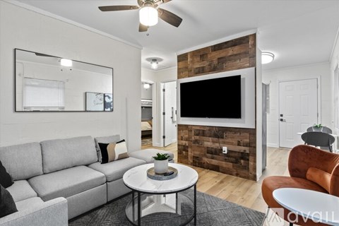 A living room with a grey couch, a white coffee table, and a wooden accent wall.