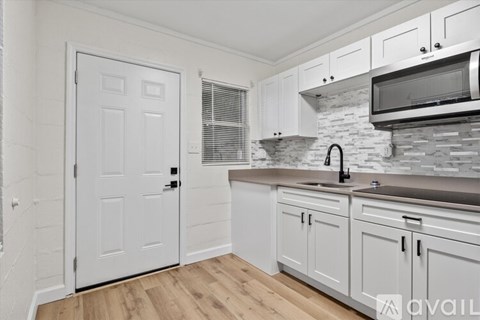 A kitchen with white cabinets and a white door.