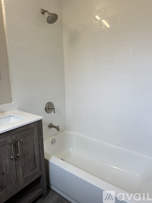 A white tiled bathroom with a white bathtub and a white sink.