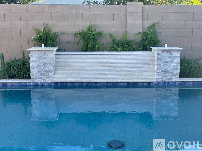 A pool with a stone pillar and a wooden deck.