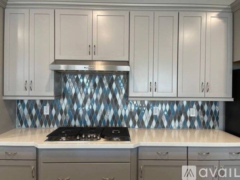 A kitchen with white cabinets and a blue and white backsplash.