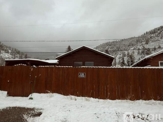 A wooden fence with a sign on it in front of a house.