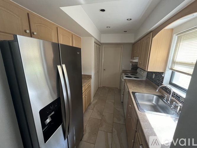 A kitchen with a black refrigerator and wooden cabinets.