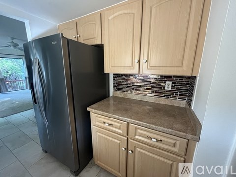A black refrigerator sits next to a counter with wooden cabinets.