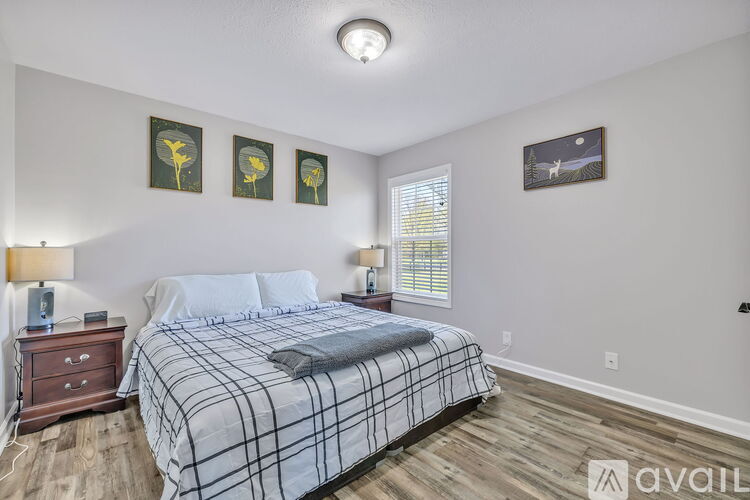 A bedroom with a bed, nightstand, and pictures on the wall.