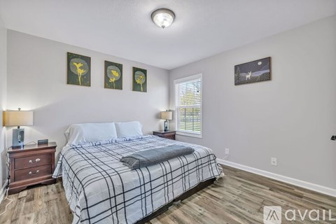 A bedroom with a bed, nightstand, and pictures on the wall.