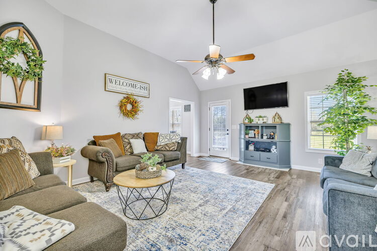 A living room with a sofa set, a coffee table, and a flat screen TV mounted on the wall.