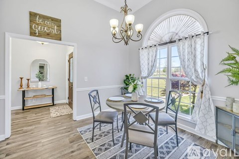 A dining room with a table set for two and a chandelier hanging from the ceiling.