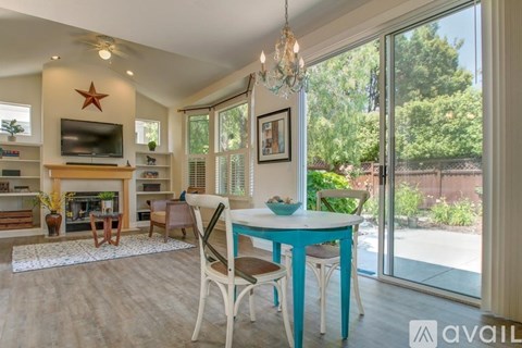 A living room with a fireplace, a dining table with chairs, and a television.