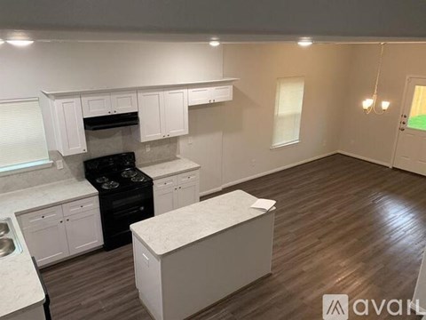 A kitchen with white cabinets and a wooden floor.
