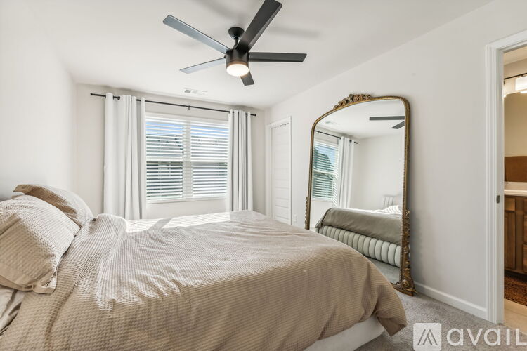 A bedroom with a bed, a mirror, and a ceiling fan.
