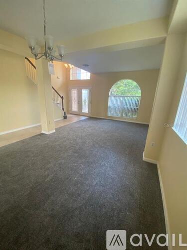 A spacious room with a carpeted floor and a staircase leading to another level.