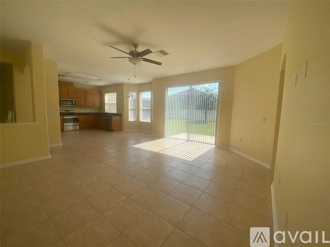 A spacious living room with a ceiling fan and tiled flooring.