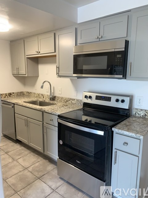 A kitchen with a black stove top oven and a black microwave above it.