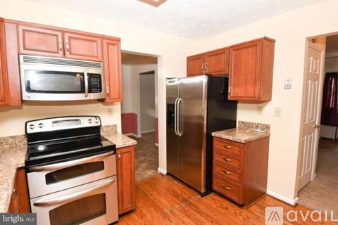 A kitchen with wooden cabinets and a stainless steel refrigerator.