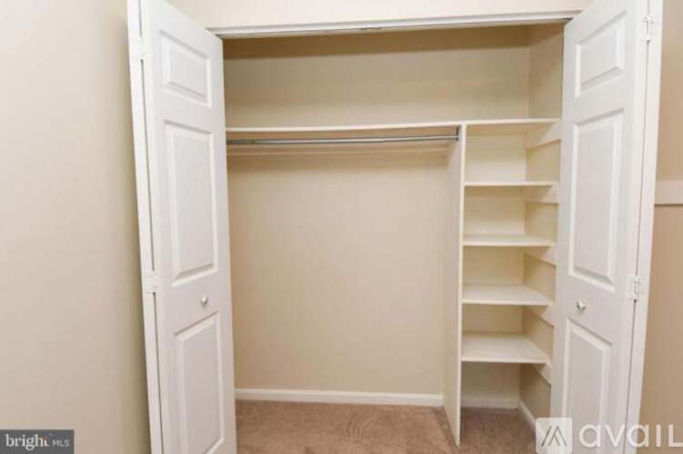 A white closet with shelves and doors open.