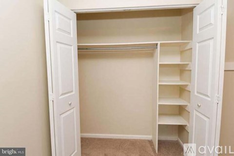 A white closet with shelves and doors open.