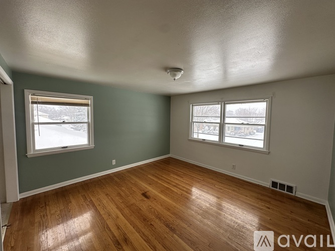 A room with wooden floors and two windows.