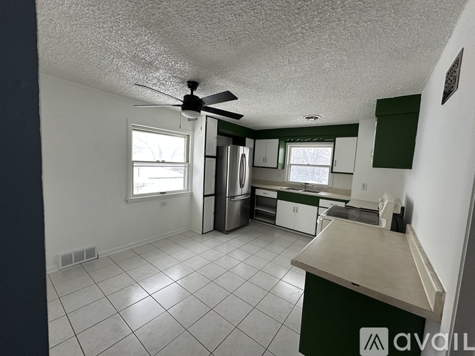 A kitchen with white tile floors and green cabinets.