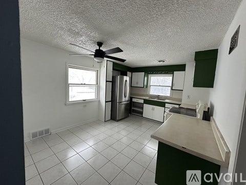 A kitchen with white tile floors and green cabinets.