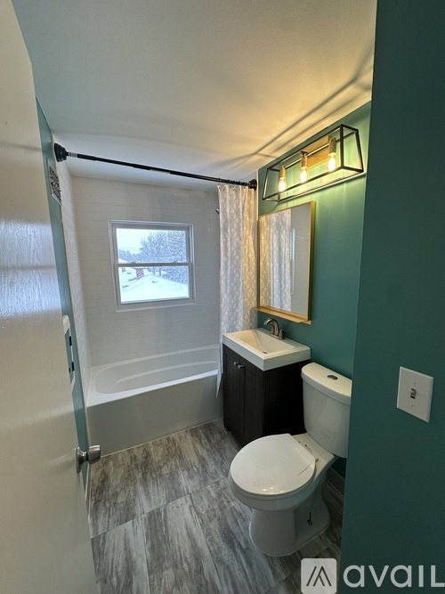 A bathroom with a toilet, sink, and a window.