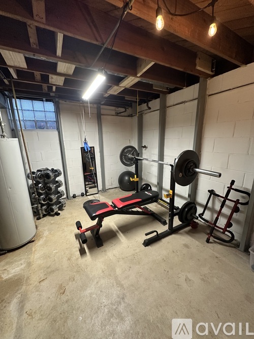 A gym with a bench, weights, and a barbell.
