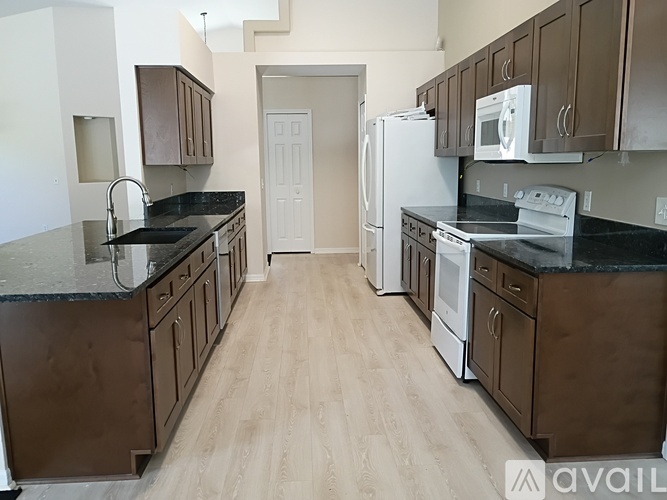 A kitchen with brown cabinets and black countertops.