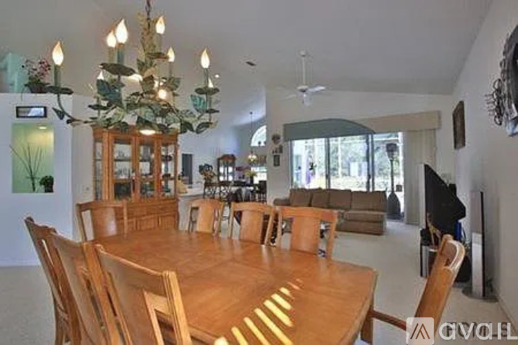 A large wooden dining table with chairs and a chandelier in a spacious room.