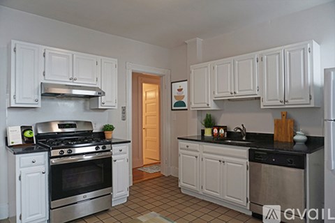 A kitchen with white cabinets and black countertops.