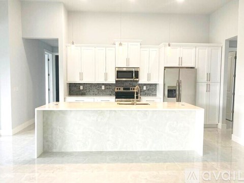A modern kitchen with white cabinets and a marble island.