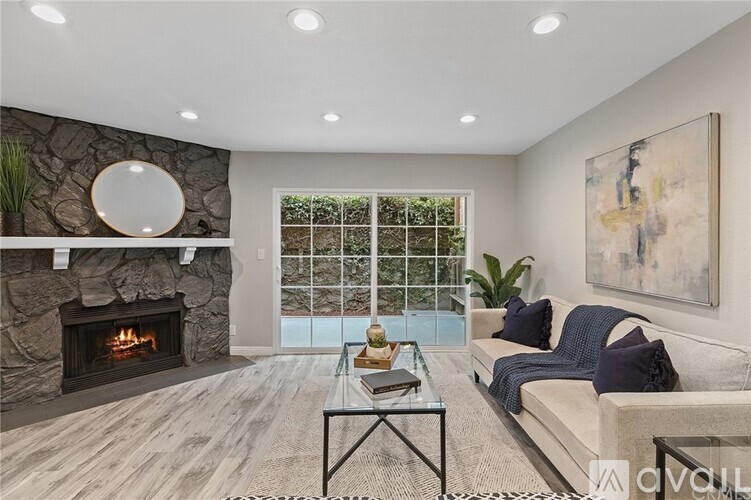 A modern living room with a stone fireplace and a glass table.