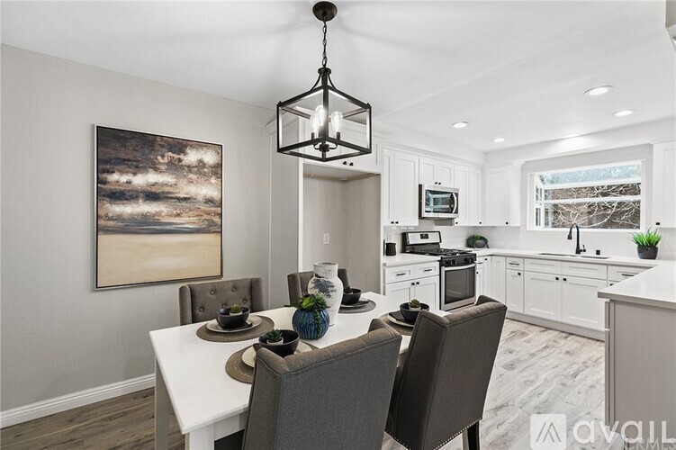 A dining room with a table set for two and a kitchen area in the background.