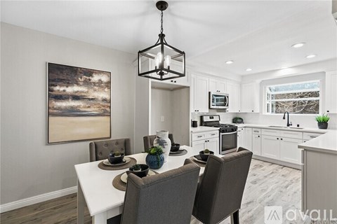 A dining room with a table set for two and a kitchen area in the background.