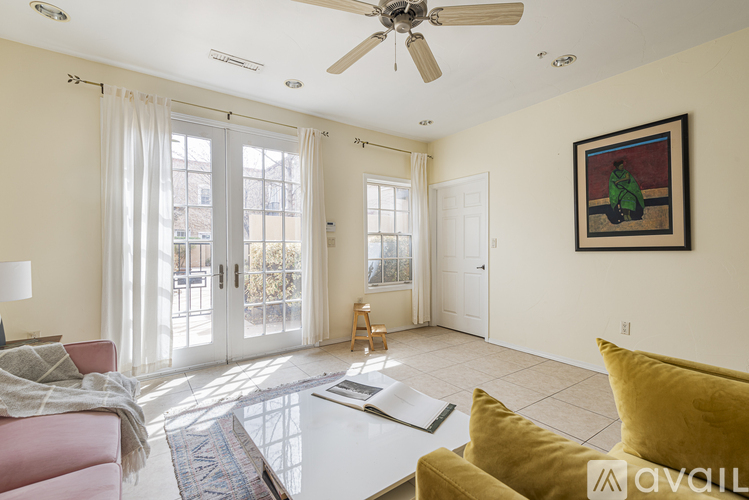 A living room with a pink couch, a yellow couch, a white coffee table, and a painting on the wall.