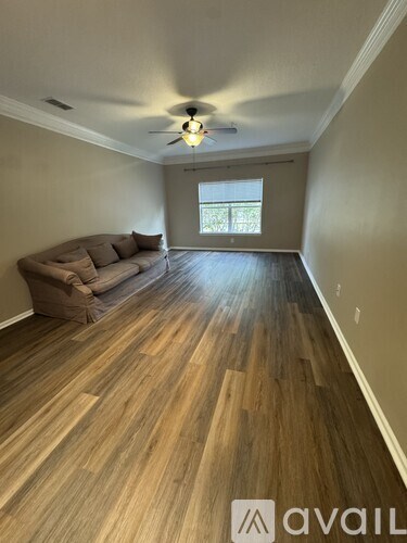 A living room with a couch and a ceiling fan.
