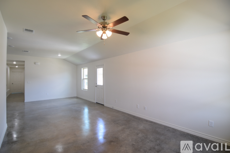 A spacious room with a ceiling fan and two windows.