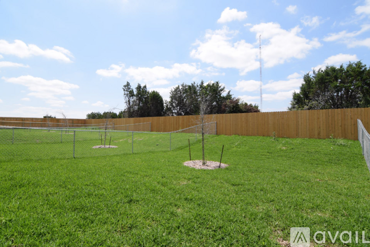 A grassy field with a fence and a couple of trees.