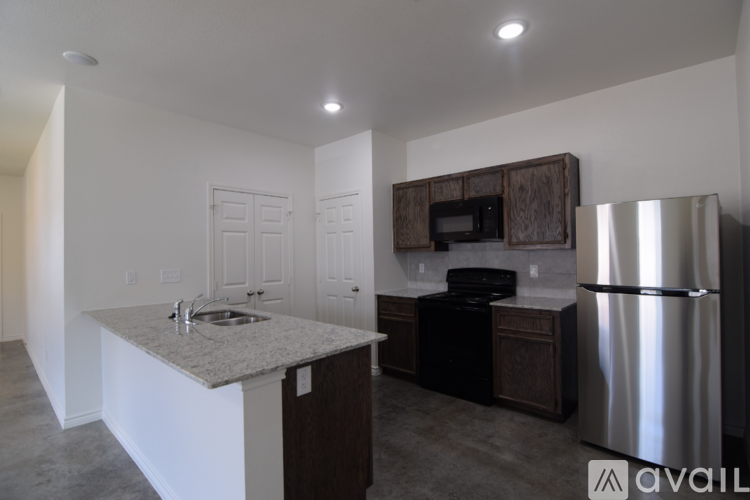 A kitchen with a stainless steel refrigerator and a granite countertop.