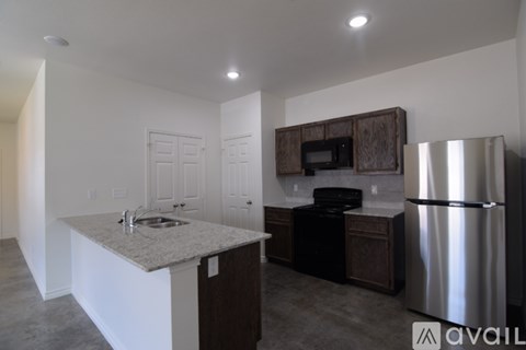 A kitchen with a stainless steel refrigerator and a granite countertop.