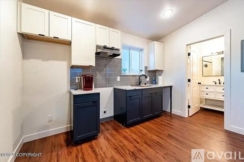 A kitchen with dark wood floors and white cabinets.