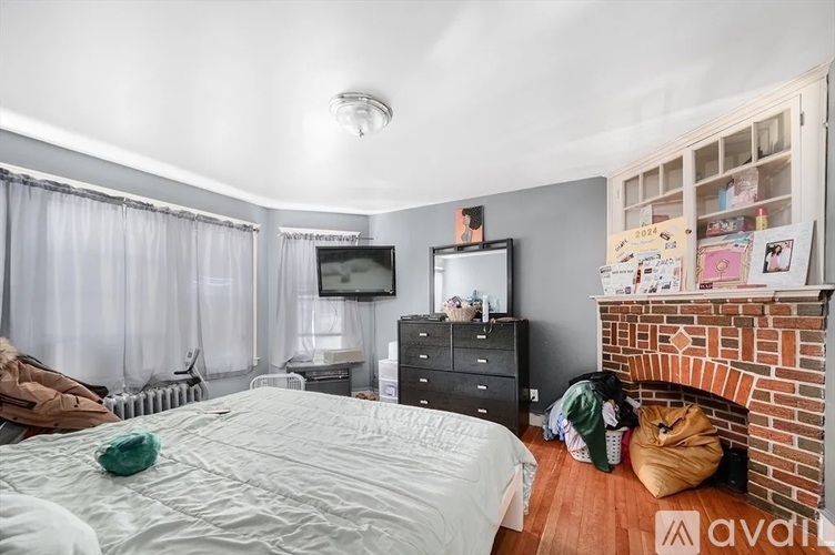A bedroom with a large bed, a TV, a dresser, and a fireplace.