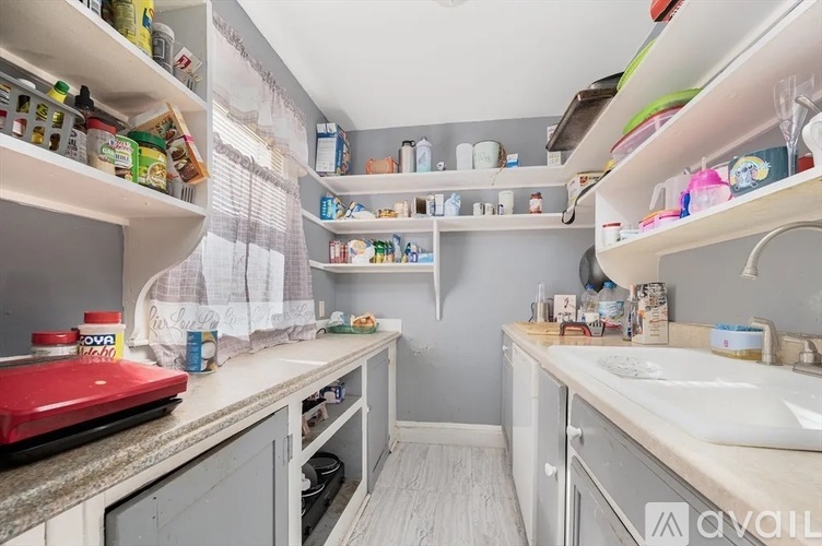 A kitchen with white cabinets and a red toaster on the counter.