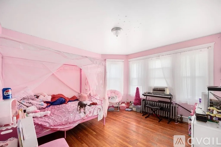 A child's bedroom with a pink canopy bed and a white chair.
