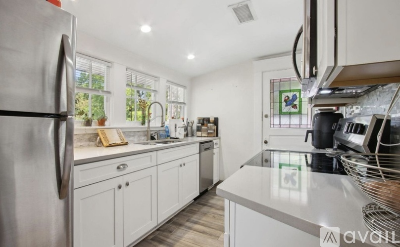 A kitchen with white cabinets and a stainless steel refrigerator.