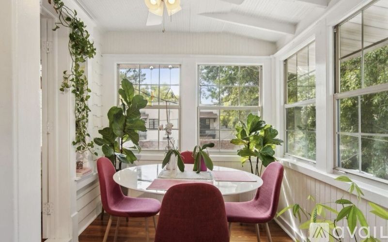 A dining room with a white table and red chairs.
