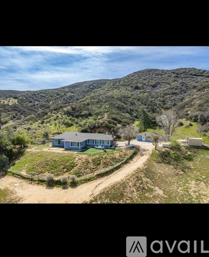 A house is situated on a hill with a dirt road leading to it.