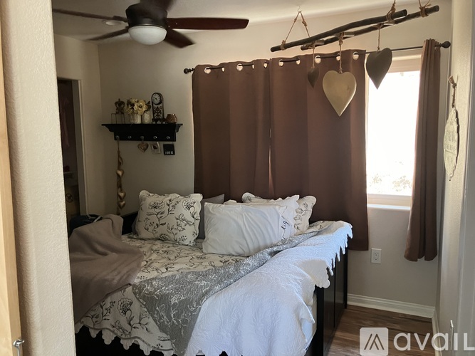 A bedroom with a bed, a ceiling fan, and a window with curtains.