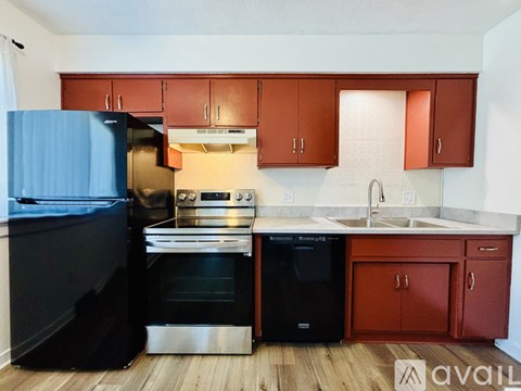 A kitchen with wooden cabinets and a black refrigerator.