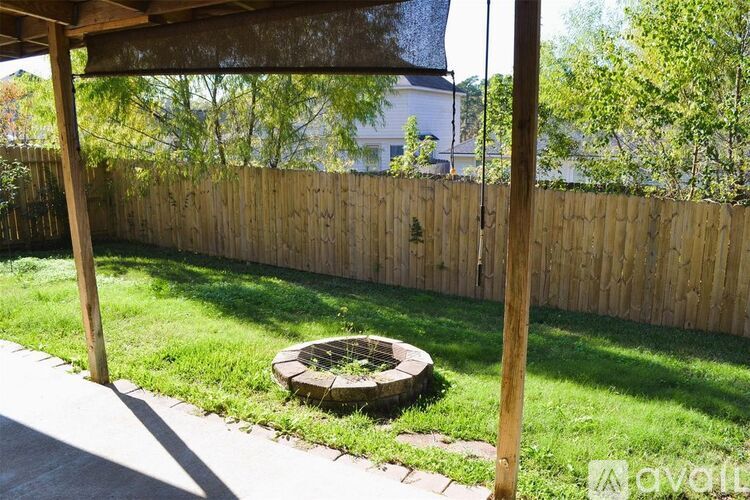 A backyard with a wooden fence and a fire pit.