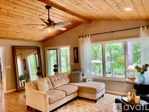 A living room with a beige sofa and a ceiling fan.